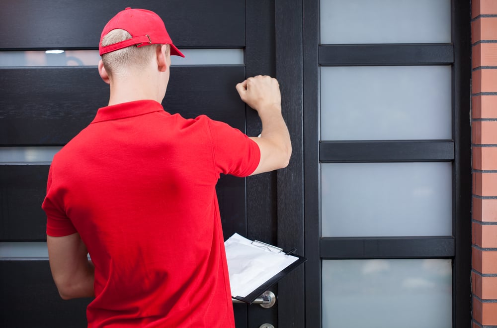 Back view of a delivery man knocking on the clients door